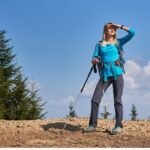 Woman hiker with trekking poles looking at mountain view