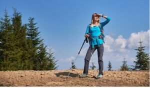 Woman hiker with trekking poles looking at mountain view